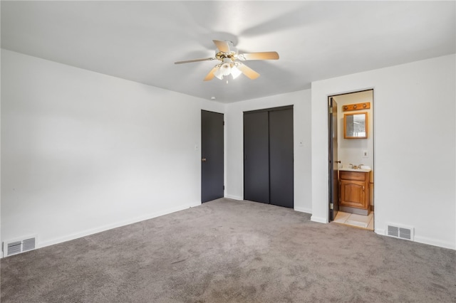 unfurnished bedroom featuring light carpet, a closet, ensuite bath, and ceiling fan