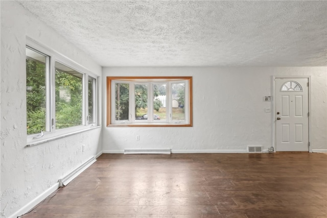 interior space featuring dark wood-type flooring, a textured ceiling, and baseboard heating