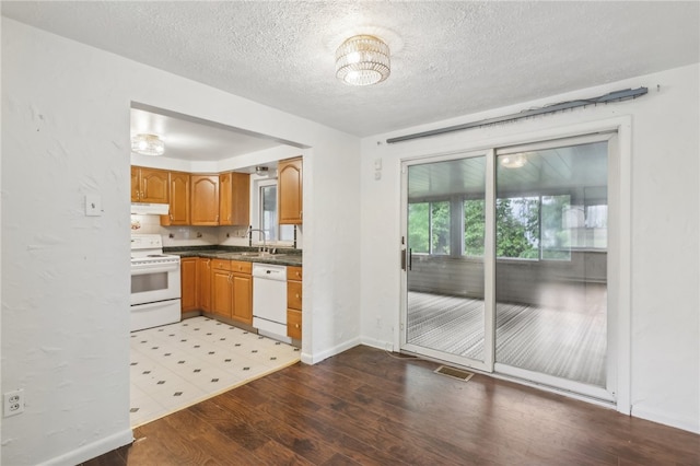 kitchen featuring light tile patterned flooring, white appliances, sink, and a textured ceiling