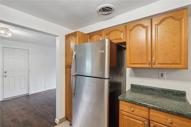 kitchen with dark wood-type flooring and stainless steel refrigerator