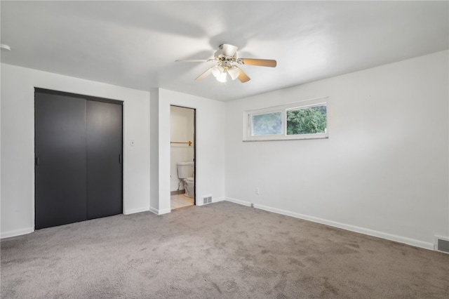 unfurnished bedroom with light colored carpet, a closet, ensuite bath, and ceiling fan