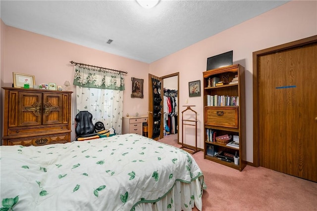 carpeted bedroom with a spacious closet, a textured ceiling, and a closet