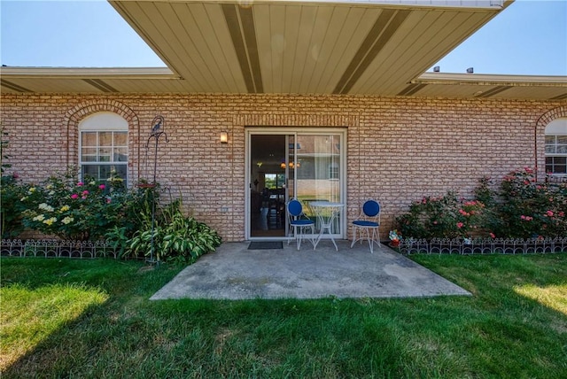 property entrance featuring a lawn and a patio area