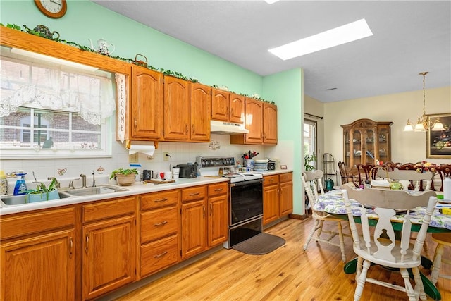 kitchen with electric range oven, decorative light fixtures, sink, decorative backsplash, and light wood-type flooring