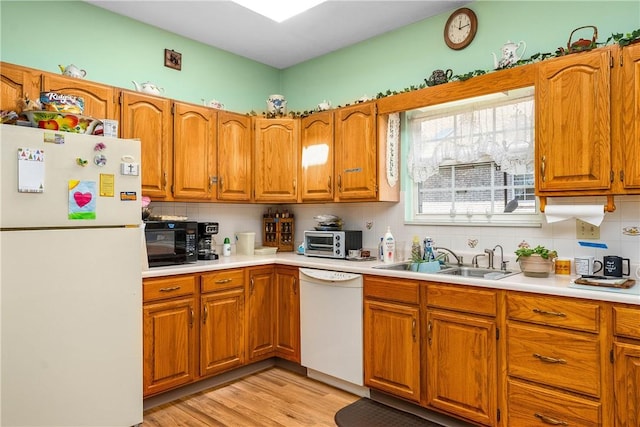 kitchen featuring white appliances, light hardwood / wood-style floors, sink, and backsplash