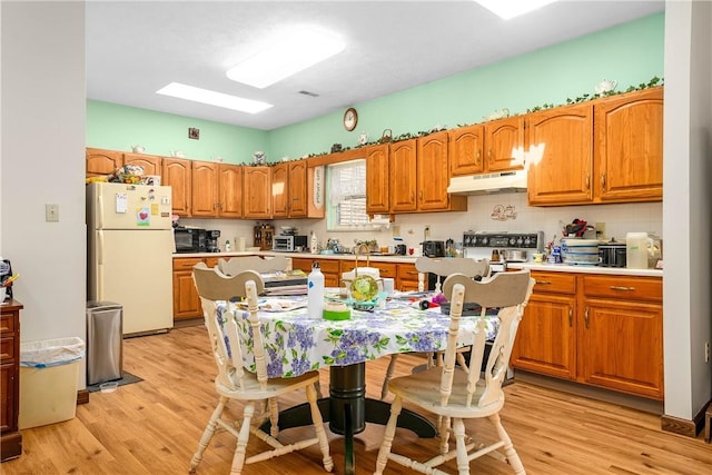 kitchen featuring white refrigerator, decorative backsplash, electric range, and light hardwood / wood-style flooring