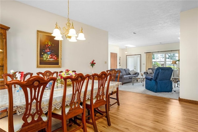 dining area featuring an inviting chandelier, a textured ceiling, and light wood-type flooring