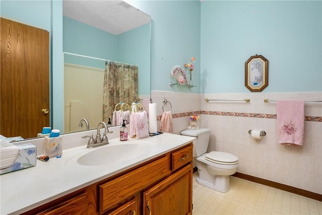 bathroom with vanity, toilet, a shower with shower curtain, and tile walls