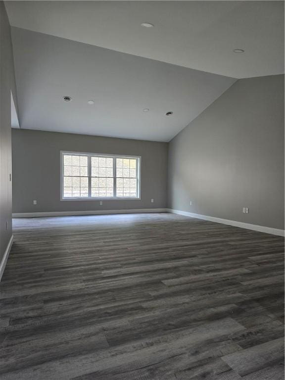 spare room with lofted ceiling and dark wood-type flooring