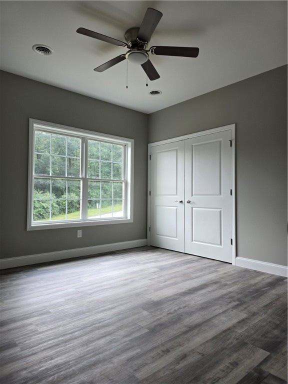 unfurnished bedroom with ceiling fan, hardwood / wood-style flooring, and a closet