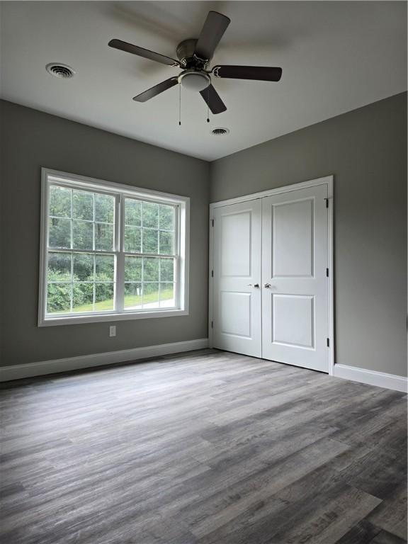 unfurnished bedroom with ceiling fan, wood-type flooring, and a closet