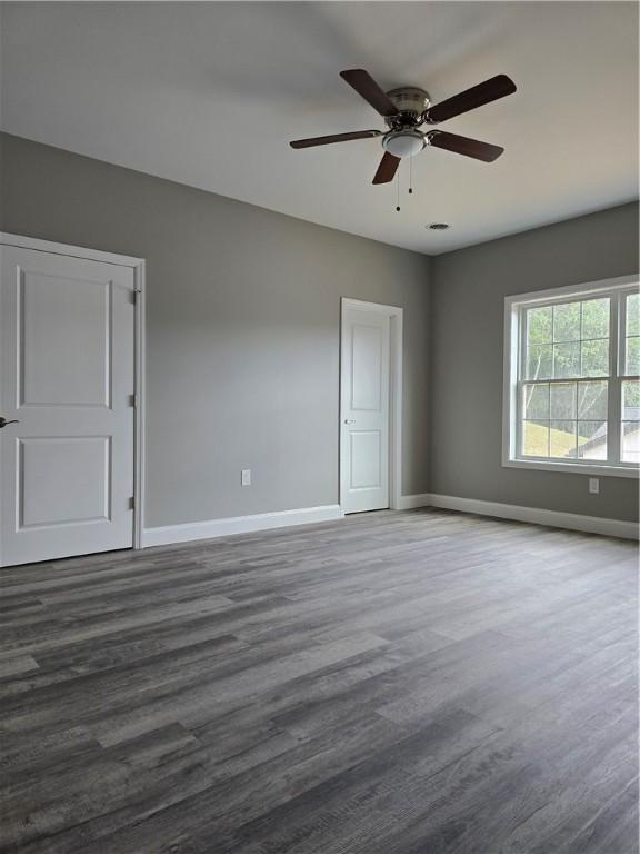 empty room featuring dark hardwood / wood-style flooring and ceiling fan