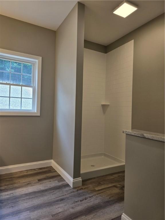 bathroom featuring tiled shower and wood-type flooring