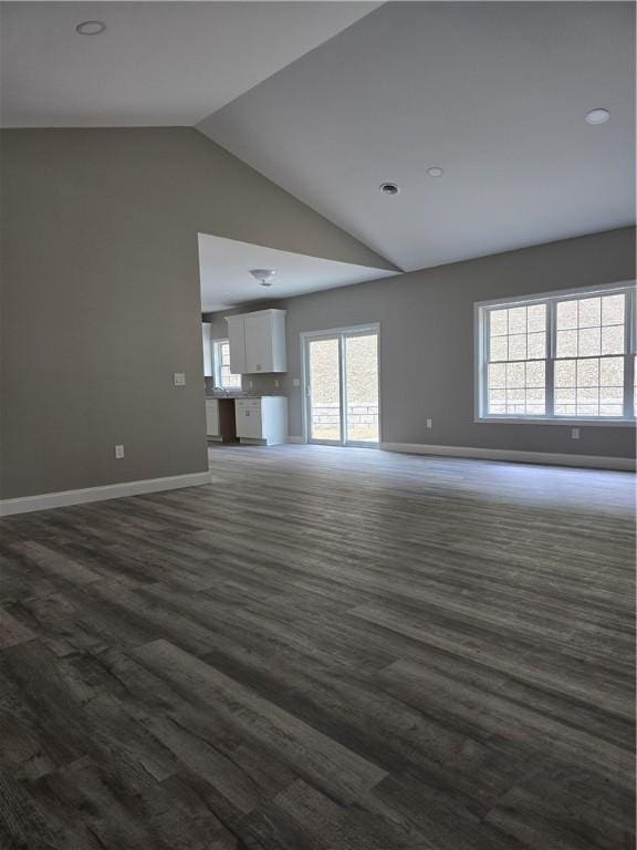 unfurnished living room featuring vaulted ceiling and dark wood-type flooring