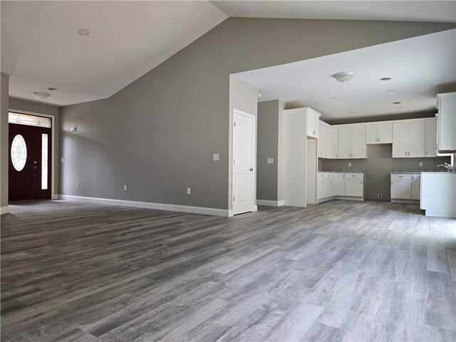 unfurnished living room featuring wood-type flooring and high vaulted ceiling