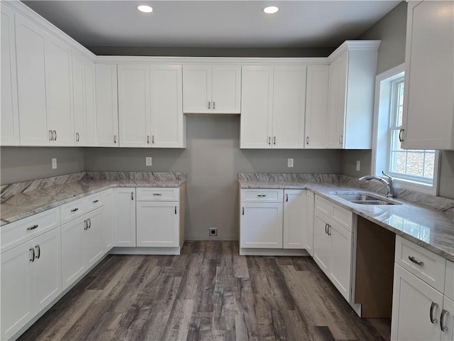 kitchen with light stone countertops, sink, white cabinets, and dark hardwood / wood-style floors