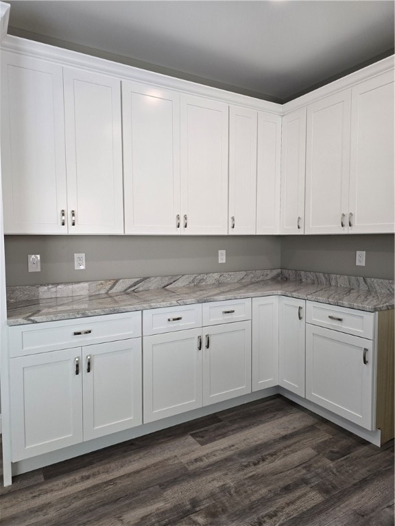 kitchen featuring white cabinets, light stone counters, and dark wood-type flooring