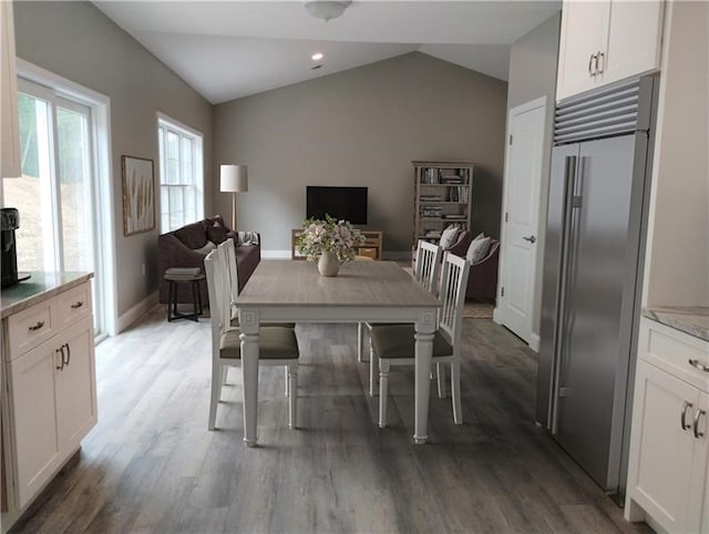 dining area with hardwood / wood-style flooring and vaulted ceiling