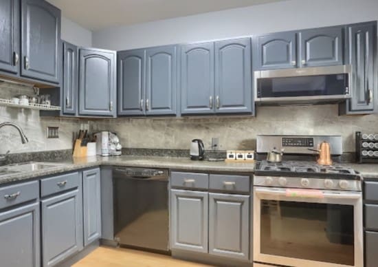 kitchen featuring appliances with stainless steel finishes, tasteful backsplash, sink, light wood-type flooring, and dark stone counters