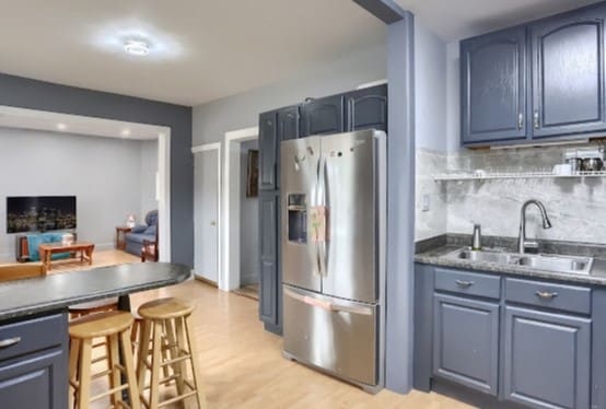 kitchen featuring backsplash, light wood-type flooring, sink, stainless steel refrigerator with ice dispenser, and blue cabinets