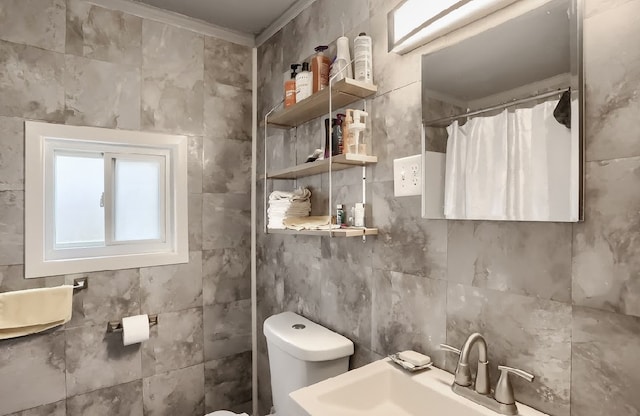 bathroom with curtained shower, crown molding, tile walls, toilet, and sink