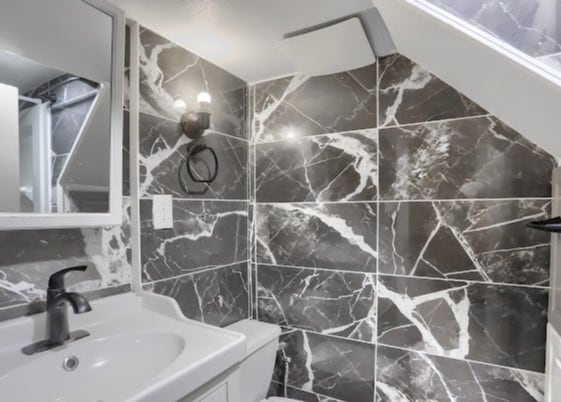 bathroom with tile walls, toilet, and vanity