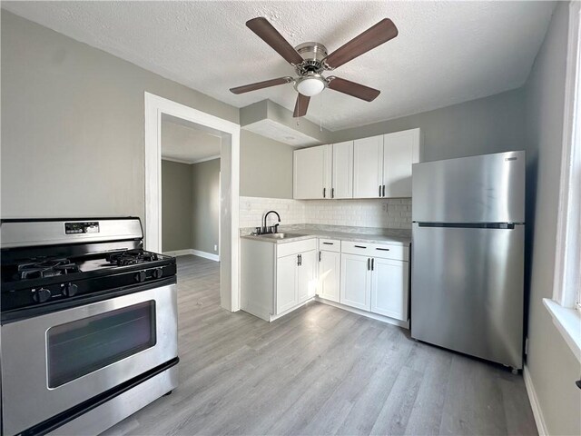 kitchen featuring appliances with stainless steel finishes, decorative backsplash, sink, and white cabinetry