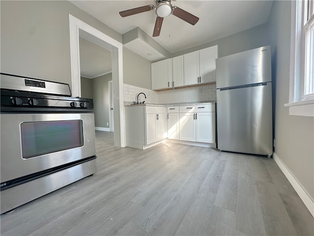 kitchen with white cabinets, backsplash, ceiling fan, stainless steel appliances, and light hardwood / wood-style floors