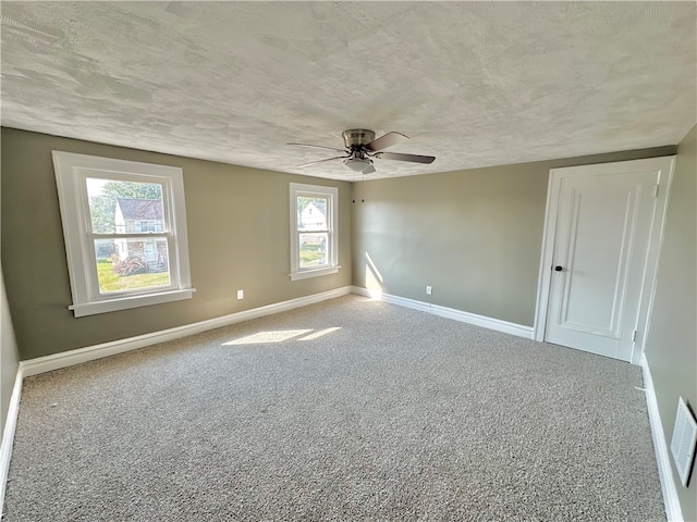 carpeted empty room featuring a textured ceiling, ceiling fan, and plenty of natural light