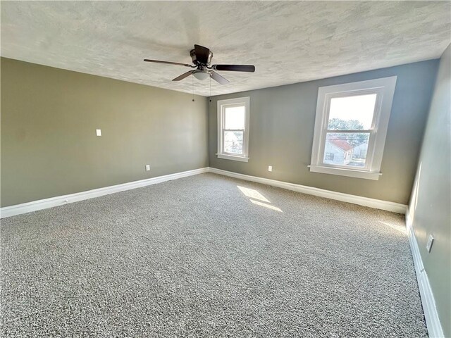 carpeted empty room featuring ceiling fan and a textured ceiling