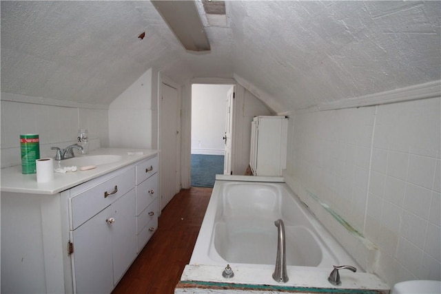 814 Etna St, Mckees Rocks, PA 15136 - bathroom with a bathtub, wood finished floors, a textured ceiling, vaulted ceiling, and vanity