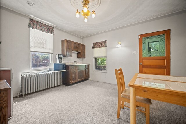 carpeted dining space featuring radiator, sink, and an inviting chandelier