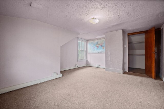 unfurnished bedroom featuring vaulted ceiling, light colored carpet, and a textured ceiling