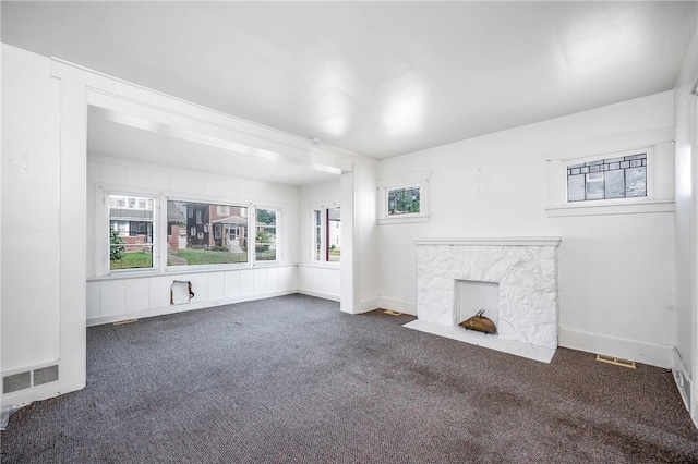 unfurnished living room featuring a fireplace and dark colored carpet