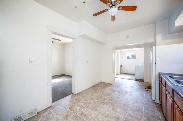 kitchen with white fridge, sink, light tile patterned floors, and ceiling fan