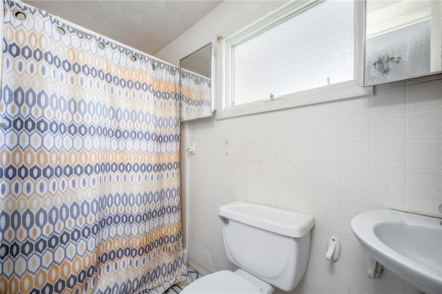 bathroom with sink, toilet, and tile walls