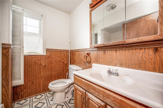 bathroom featuring vanity, tile patterned floors, wooden walls, and toilet