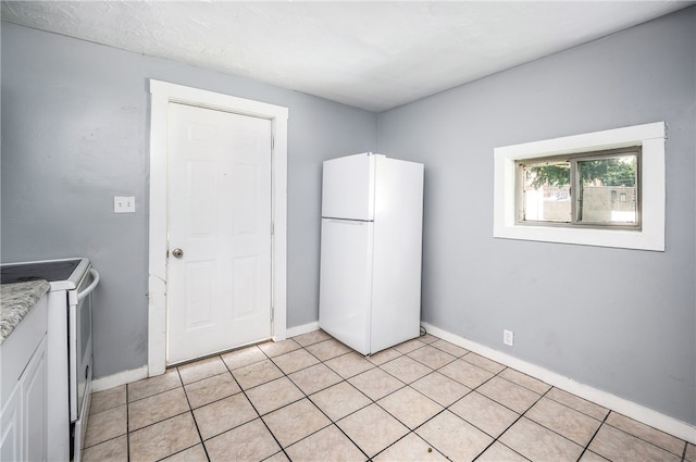 kitchen with light tile patterned floors, white refrigerator, and range with electric stovetop