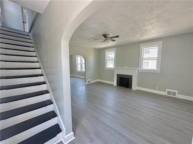 unfurnished living room featuring a textured ceiling, ceiling fan, a fireplace, and hardwood / wood-style flooring