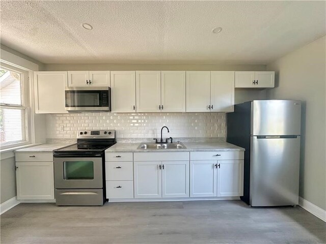 kitchen with white cabinetry, sink, stainless steel appliances, and a textured ceiling