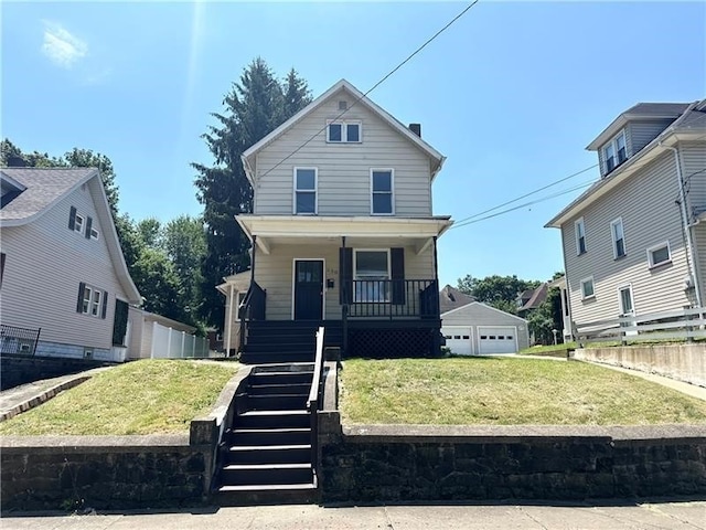 view of front facade with covered porch, an outbuilding, a garage, and a front lawn