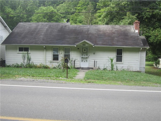 view of front of house featuring a front yard, a chimney, and roof with shingles