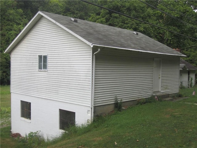 view of side of home featuring roof with shingles and a lawn