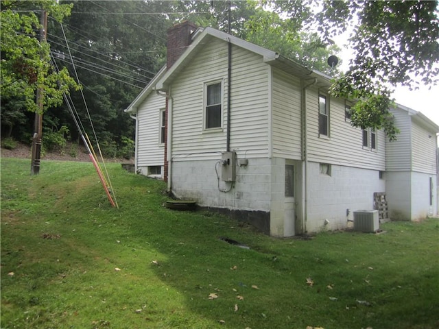 view of home's exterior featuring a yard, central AC, and a chimney