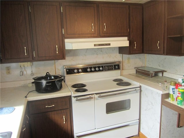 kitchen with under cabinet range hood, light countertops, double oven range, open shelves, and tasteful backsplash