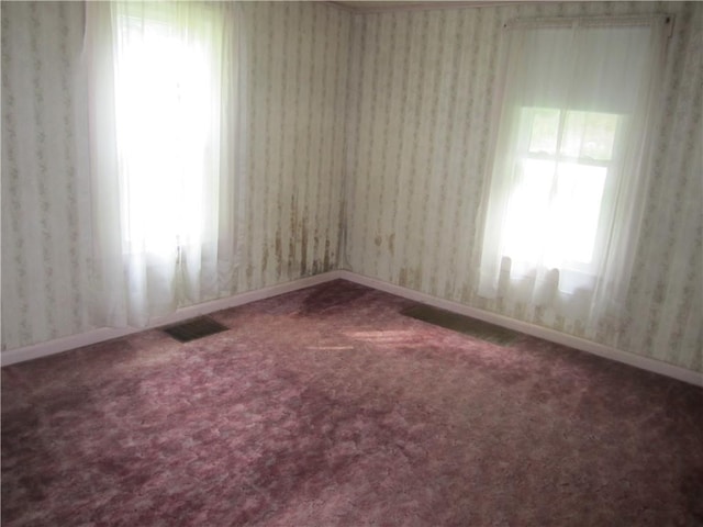 unfurnished room featuring wallpapered walls, baseboards, visible vents, and carpet flooring