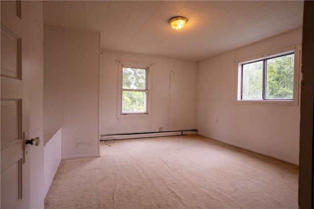 unfurnished room with light carpet, baseboard heating, and plenty of natural light