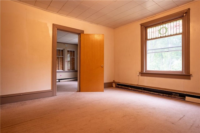 carpeted spare room with a baseboard heating unit