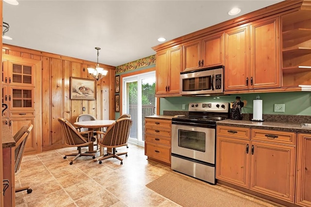 kitchen featuring wood walls, a chandelier, pendant lighting, and stainless steel appliances