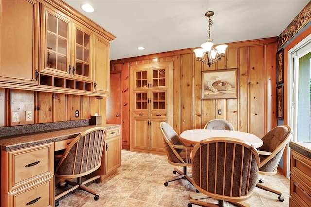 office with a chandelier, a healthy amount of sunlight, wooden walls, and built in desk